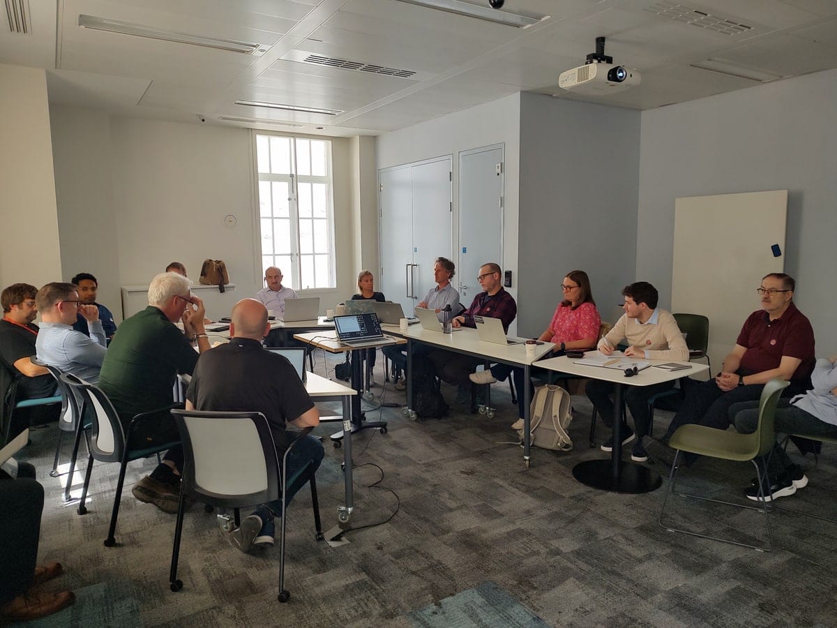 The same room from the other side, with a projector overhead and attendees working at laptops.